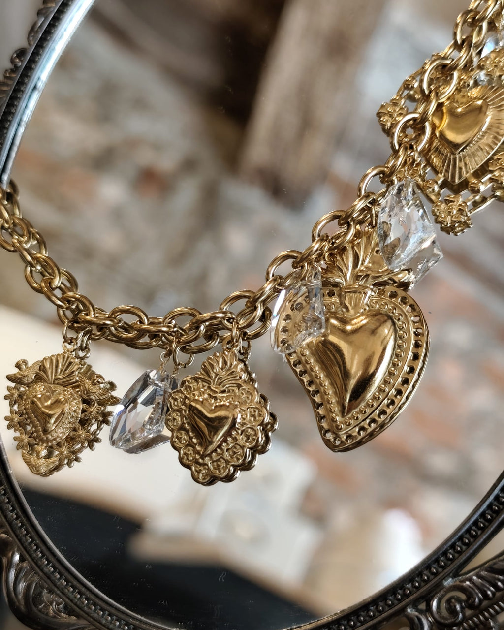 Collana charm dorata con cuori sacri e cristalli